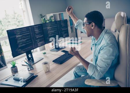 Side shot of crazy young guy celebrating his code works without bugs he raised fists up hooray software developer in office workspace Stock Photo