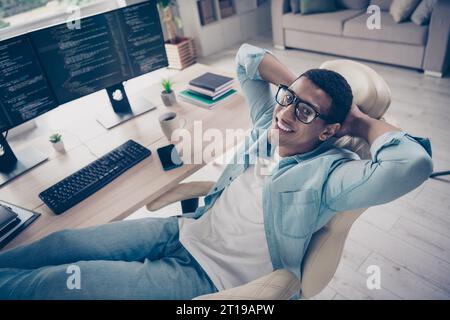 Photo of smiling young positive guy expert back end development website software optimization app relaxing hands head in modern workspace Stock Photo