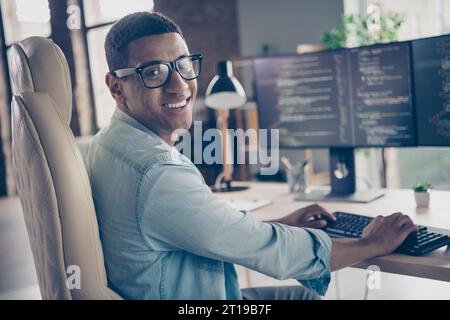 Photo of expert guy developer programmer looking at camera smiling when editing code creating new app in office workplace next to computer Stock Photo