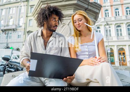 Two engineering students review notes on wind energy and the girl holds a small wind turbine Stock Photo