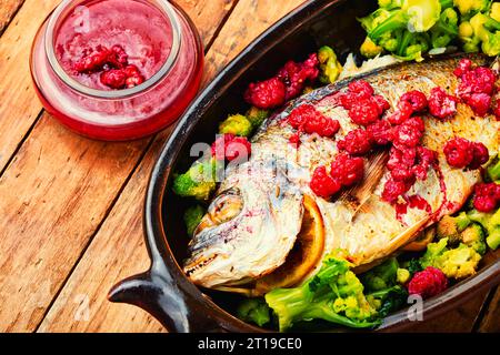 Tasty baked whole fish in fruit marinade on old wooden table Stock Photo