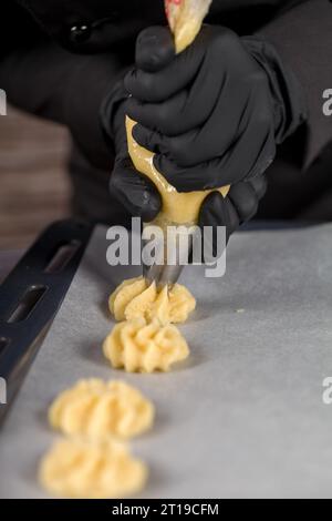 An Individual in Black Gloves Squeezes Dough from a Pastry Bag to make Cookies Using a Pastry Bag Stock Photo