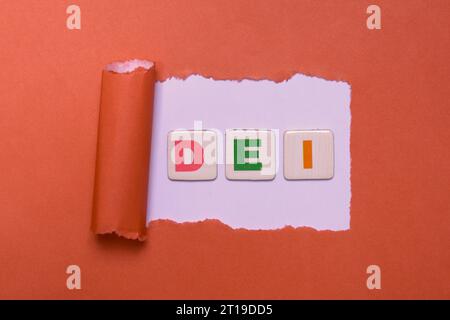 DEI Letters on Torn Red Paper. Symbol of Diversity, Equity, Inclusion. Words DEI, Diversity, Equity, Inclusion Created with Tiles on a Red Background. Stock Photo