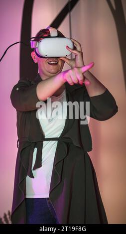 Young woman enjoying immersive multimedia experience using virtual reality glasses in a natural history museum playroom. Stock Photo