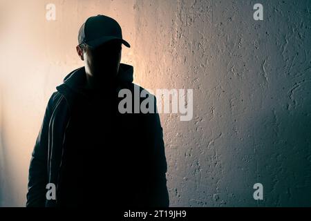 Criminal, suspicious stranger or stalker. Person with face in dark shadow. Anonymous man, terrorist suspect or gangster silhouette figure. Stock Photo