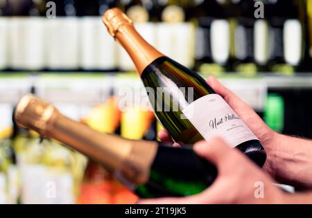 Sparkling wine in alcohol store. Champagne or prosecco in liquor shop. Man holding two bottles in hands, choosing drink. Stock Photo