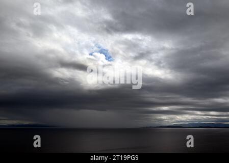 A storm approaching with black clouds on the coast of the Isles of Skye, Scotland. A blue hole through the clouds is still visible. Stock Photo