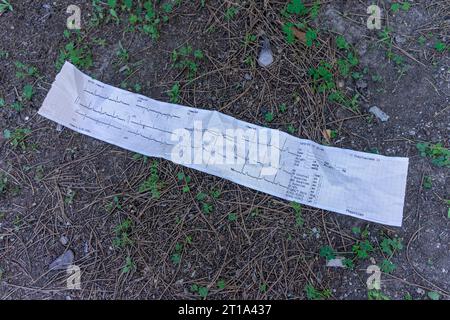 Abandoned ECG tracing on the ground, a poignant symbol of forgotten medical history. Stock Photo