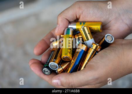 Hands holding stacks of batteries ready for recycling. Stock Photo