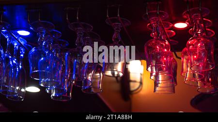 French Bar, Empty upside-down wine glasses hanging from the bar in a restaurant in France. French flag tricolor illumination. Nightlife bannner Stock Photo