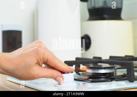 The woman turned on the gas stove and adjusted the gas supply. Close-up. Stock Photo
