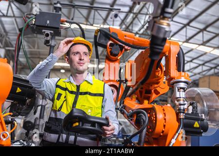 Smart modern engineer male using modern robot technology. Robotic welding arm setup in automation production process in factory Stock Photo