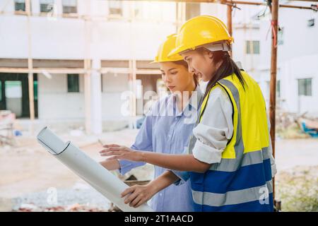 Engineer women builder working at construction site join architect teamwork looking at project floor plan Stock Photo