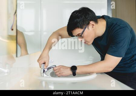 man fix repair bathroom sink tap faucet pipe leak husband working as handyman at home. Stock Photo