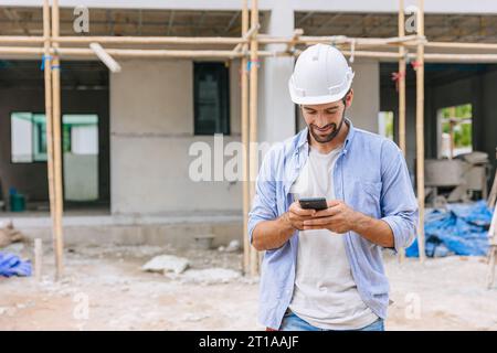 happy foreman builder using smart phone calling business contact in construction site. construction engineer or architect with modern connection techn Stock Photo
