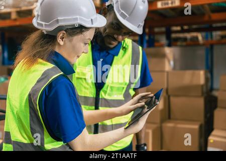 Warehouse cargo team training new staff using inventory management technology system in wireless tablet working teamwork together Stock Photo