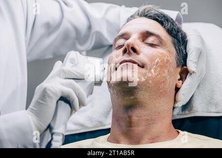 Skin doctor using HIFU resurfacing facial skincare treatment technology with adult male to reduce wrinkles and scars at anti aging clinic Stock Photo