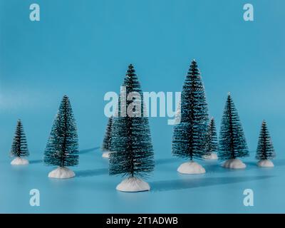 The photo shows several decorative artificial Christmas trees located on a bright blue background. The blue background creates a beautiful contrast an Stock Photo