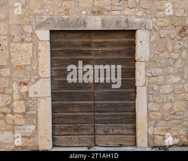 old wooden door in the wall made from limestone Stock Photo