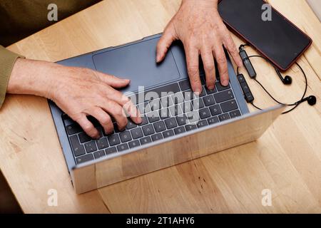 older woman's hands typing on laptop Stock Photo