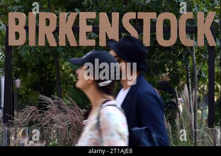 New York, USA. 12th Oct, 2023. People walk past the Birkenstock shoe company sign set up at a public interactive experience in conjunction with the shoe company's IPO launch on Wall Street the day before, New York, NY, October 12, 2023. Birkenstock shoes company debuted on the New York Stock exchange on Wed. October 11, under the symbol BIRK, but closed 13% down at the end of trading day. (Photo by Anthony Behar/Sipa USA) Credit: Sipa USA/Alamy Live News Stock Photo