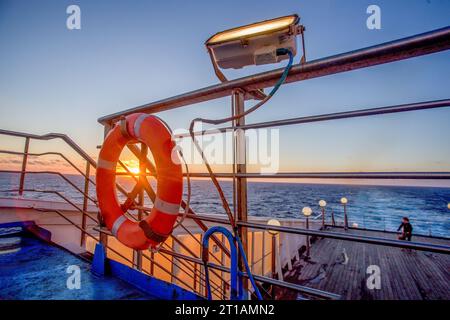 Awe pink sunrise  on  Italian ferry  (which connect Sicily island with mainland) for example - Genoa) .  Lantern fromm night time . Woman  walk  a dog Stock Photo