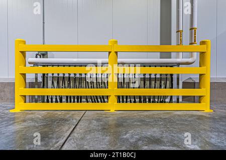 Yellow guard rail and piping for floor warming on loading dock in a newly constructed industrial refrigeration (cold-storage) facility loading dock. Stock Photo