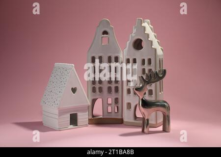House shaped candle holders and silver deer on pink background Stock Photo
