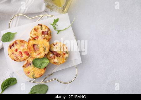 Freshly baked bacon and egg muffins with cheese on light gray table, flat lay. Space for text Stock Photo