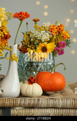 Beautiful autumn composition with pumpkins and flowers on wicker table Stock Photo