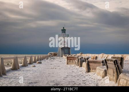 thick Ice formations over the guard rails in the pier. and benches, Winter  landscape on the lake with lighthouse and stormy sky., winter wonderland Stock Photo