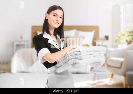 Portrait of beautiful chambermaid with clean towels in bedroom Stock Photo