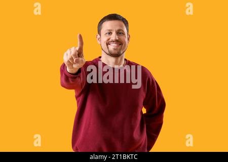 Handsome man using virtual screen on yellow background Stock Photo