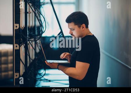 System administrator working on laptop standing near multi-screen LED panel and preparing for presentation Stock Photo