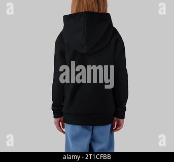 Template of a black hoodie on a blonde girl, back view, shirt for design, print, branding. Mockup of warm kid's clothing, isolated on background. Prod Stock Photo