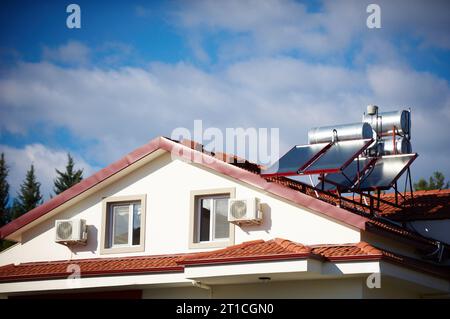 Solar heaters on the roof of the house against blue sky. Stock Photo