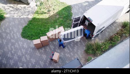 High Angle View Of Delivery Men Unloading The Cardboard Boxes From Truck Stock Photo