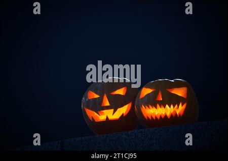 Two glowing Halloween Pumpkins on a dark background. Stock Photo