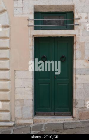 Old door with metal knocker surrounded by hand-crafted marble blocks Stock Photo
