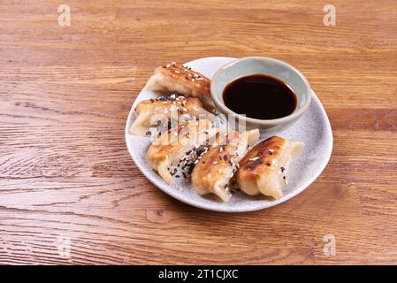 Freshly cooked dumplings gedza with soy sauce. On wooden background. Stock Photo