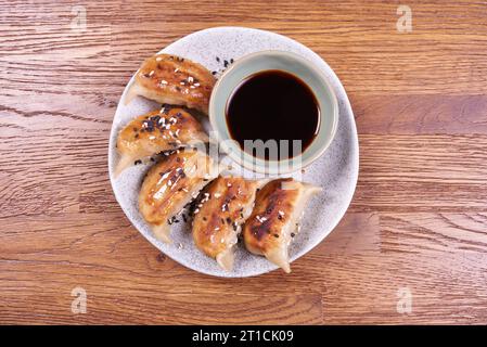 Freshly cooked dumplings gedza with soy sauce. On wooden background. Stock Photo