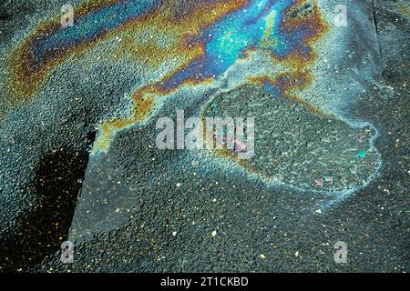 Colored oil stains close up, the color of the gasoline stain on the pavement road as a texture or background. Stock Photo