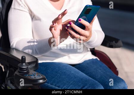 woman using wheelchair using mobile phone Stock Photo