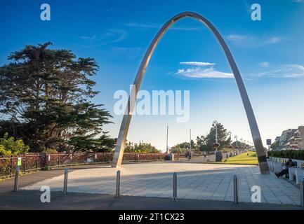 The metal arch of the Step Short Memorial to soldiers who died in World War One next to railings adorned with hand-knitted red poppies fixed to railin Stock Photo