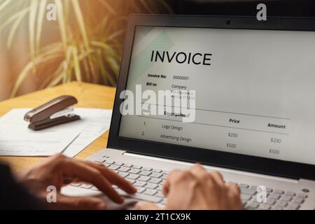 freelancer make an invoice on laptop computer at home office. business accounting Stock Photo