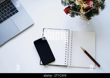 open notepad with blank sheet for new year resolutions, wishes or to do list. Laptop and smartphone on background Stock Photo