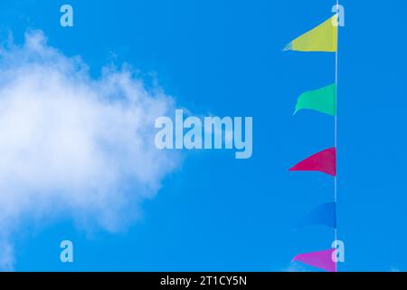 decorative colored pennants with a blue sky background and a cloud Stock Photo