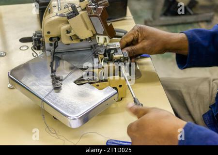 overlock machine repair african mechanic in textile industry, skilled factory workers Stock Photo