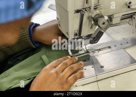 african woman entrepreneur in textile industry,  factory workers in the buttonhole machine working on workwear clothing Stock Photo