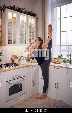 Young attractive woman practicing yoga at modern kitchen Stock Photo